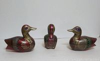 Three wood carved ducks, two larger jewelry boxes with hinged tops and one small solid carved duck figurine, showing front view of all three.