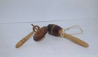 Photo of two wooden spinning tops and one catching game from Mexico, showing front view with details of shapes and finishes.