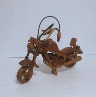 Front angle view of large wood carved motorcycle figurine on white background showing detailed front wheel, handlebars, seat and engine.