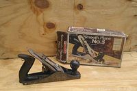 No. 3 woodworking smooth plane resting on a wooden surface with its original box in the background.