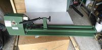 Full side view of green woodworking lathe showing bed, motor housing with power switch, tool rest, and tailstock assembly.
