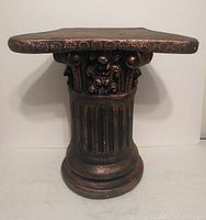 Front view of the V shaped plaster cast column showing ornate detailing and metallic finish with paint chipping.