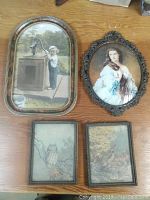All four framed vintage prints laid on wooden surface, showing frames and artwork.