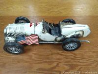 Side perspective showing the American flag decal, engine grills, wheels, and steering wheel detail on the model racecar.