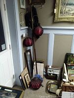 Full view of retro tall pole lamp with two red swag lamps attached, standing upright in corner with surrounding framed pictures and art.