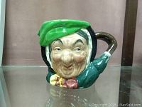 Front view showing the detailed face of the Toby mug with green hat, colorful scarf, and curved handle.