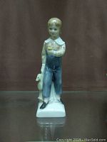 Front view of the Royal Doulton figurine 'Tom' showing the boy standing and holding a flower with the rocking horse.