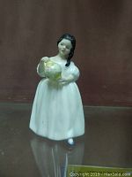 Front view of Royal Doulton Mandy porcelain figurine showing girl holding yellow floral jug.