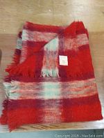 Folded Hudsons Bay mohair blanket showing red, white, and teal plaid pattern and fringed edges.