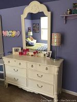 White Lexington dresser with 6 drawers and attached large mirror with carved top detail.