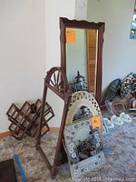Photo shows four mirrors of varied sizes, a wood wine rack with lattice design, and two small stands. One stand leans on large mirror with visible damage and soiling. Mirrors include a large dark wood framed mirror (18x53) and brackets with decorative details.