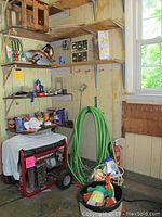 Wide shot showing a portable power generator, coiled green garden hose, paint cans, and assorted tools and hardware in a workshop environment.