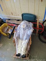 Full view of large doll in snow suit seated on Paris Champion sled with other items behind