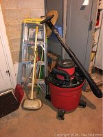 Grouped photo showing the Craftsman shop vacuum, ladder, step stool, broom, and snow shovel arranged against a wall.