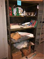 Full shelving unit showing three lanterns, lightbulbs, glass covers, tarps, shelving paper, and screen material