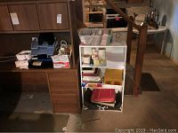 Wide shot of shelving and white bookcase with office supplies including folders, envelopes, and rolls of tape.