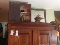 Wooden sewing drawer chest with small decorative items on top including bottles and a red container, potted plant with orange flowers prominently displayed on top edge.