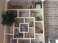 Shelf display with geodes, petrified wood, glass bottles, antler, birdhouse and decorative plants