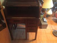 Front view of the wood roll top desk with the roll top door open revealing the cubbies and drawer layout.