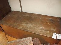 Top and side view of a rectangular wooden chest with scratches and worn finish.