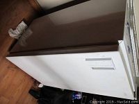 Side view of white Sanyo mini refrigerator showing surface wear and door with recessed handle.