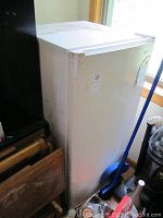 White Kenmore refrigerator showing side and front. Exterior has marks and noticeable wear.