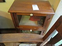 Front view of the wood vegetable bin showing top and both wire mesh doors with white knobs.