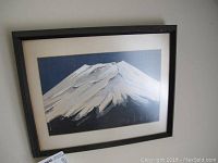 Framed print of a snow-covered mountain with a dark frame