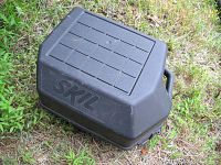 Closed black plastic carrying case with embossed 'SKIL' branding on the lid, on grass.