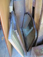 Three mirrors leaning against wood, showing different shapes and frame styles
