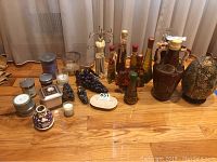 Full view of assorted candles, jewelry holder, decorative bottles, and decorative items on wood floor.