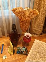 Photo showing all four glass vases, moon sculpture, and candle holder grouped together on the floor near a window and beige rug.