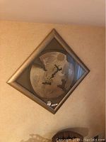 Full view of the framed circular abstract art piece hung on a wall, showing the bronze-toned metallic frame and the multi-medium textures.