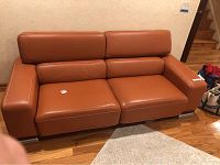 Front view of the orange-brown leather sofa on hardwood floor