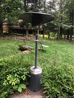Full height view of the Fire Sense propane patio heater outdoors showing the entire unit including base and heat reflector.