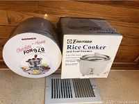 Photo showing boxed Emerson rice cooker and boxed Roshco fondue set together on floor.