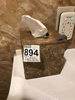 Stone tissue holder cube for tissues on bathroom counter next to electrical outlet