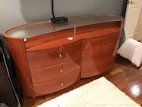 Front view of modern wooden dresser with 6 drawers and glass top.