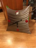 Front view of a square concave handcut metal wall clock with red ceramic quarter markers and black clock hands.