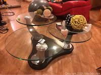 Full view of three tier glass top table with decorative balls on top, showing black base and brushed nickel supports