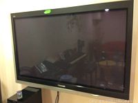 Front view of the Panasonic Viera 50-inch TV mounted on the wall with remote on stand below.