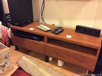 Full view of the laminate media stand with electronics and remotes on top.