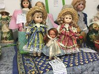 Front view showing two 7-inch porcelain dolls in country style dresses and straw hats, with a smaller 4-inch doll in front.