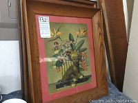 Close up of framed Asian art print with figure and flowers, in wood frame with pink matting.