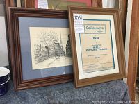 Photo of two frames side by side; left features detailed black-and-white drawing of Old North Church, Boston, framed with wooden frame and blue mat, right is wooden picture frame with matting and visible frame label.