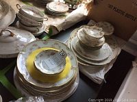 View of stacked Haviland china including various plates, bowls, and a covered dish with floral and gold designs.