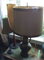 Three lamps arranged on a table near a window showing the different sizes and lampshades