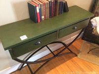 Full view of the green painted hall table with wood top and metal legs, showing the two drawers and books on top.