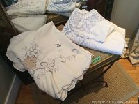 Cotton tablecloths displayed on a wooden surface showing lace details and embroidery.