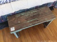 Top view of the rustic wooden bench showing weathered wooden planks on top with cracks and paint remnants.